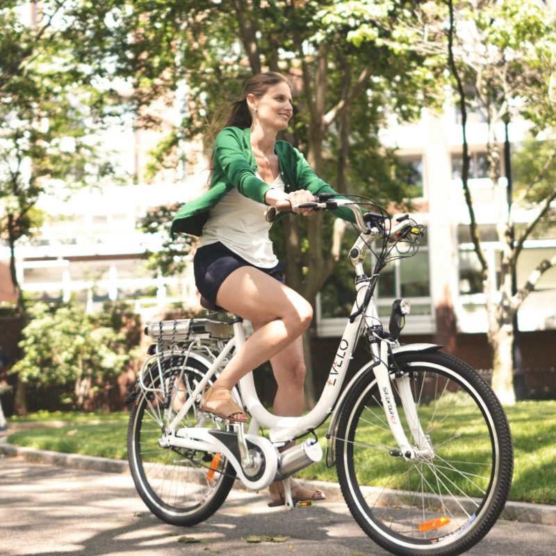 Female cyclist enjoying a sunny ride on her electric bike in the park.